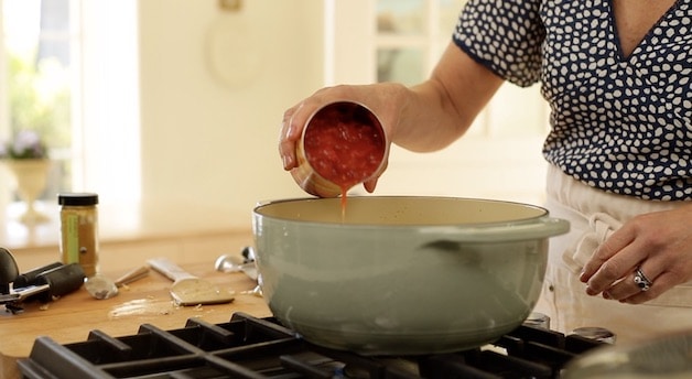 adding canned tomatoes to a large stock pot