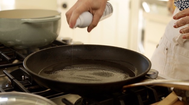 Spraying a non stick pan with coconut oil