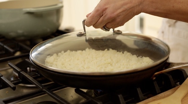 steaming cauliflower rice in a skillet