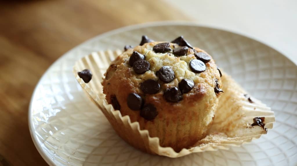 Banana Chocolate Chip Muffin on a plate with its liner peeled open