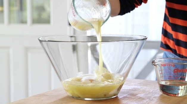 adding melted butter to a clear glass bowl
