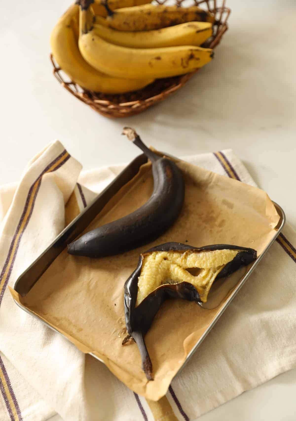 Bananas in a basket and black ripe bananas that have been roasted, sliced open.