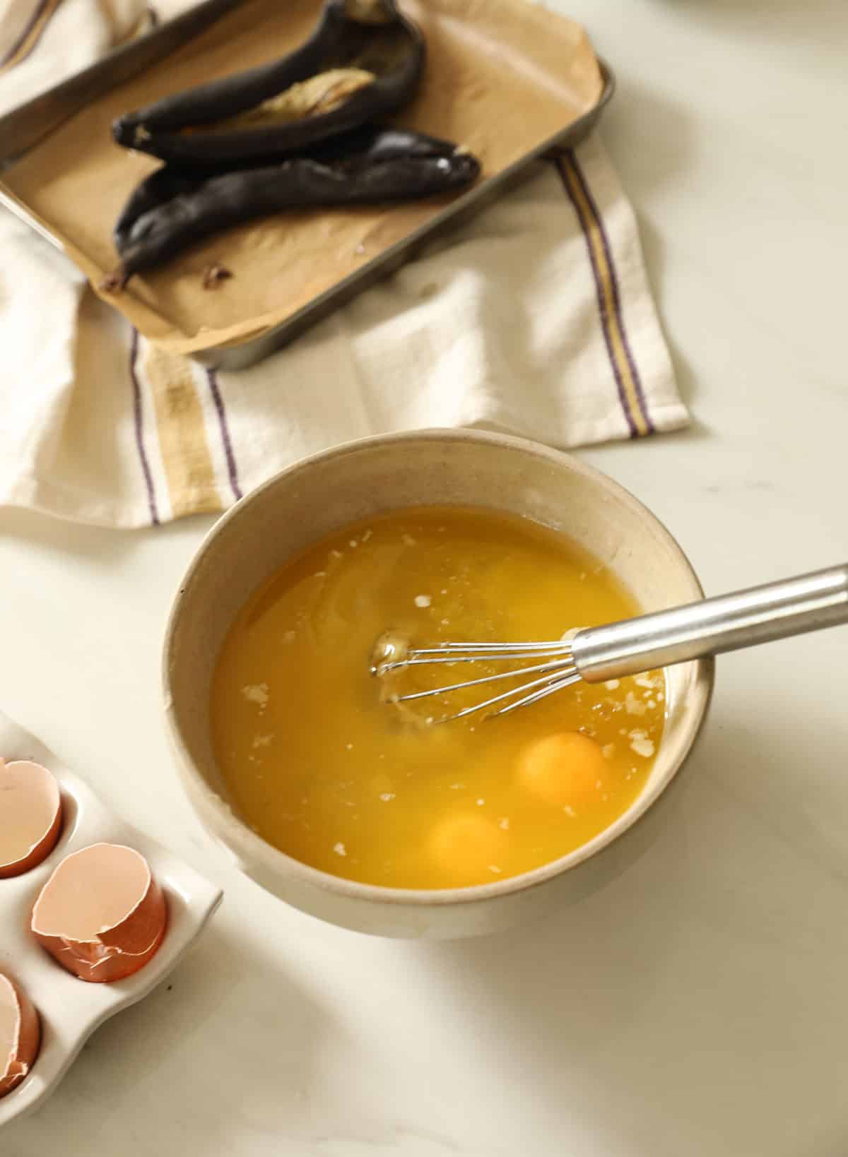 A mixing bowl with eggs, mashed bananas, melted butter and other wet ingredients.