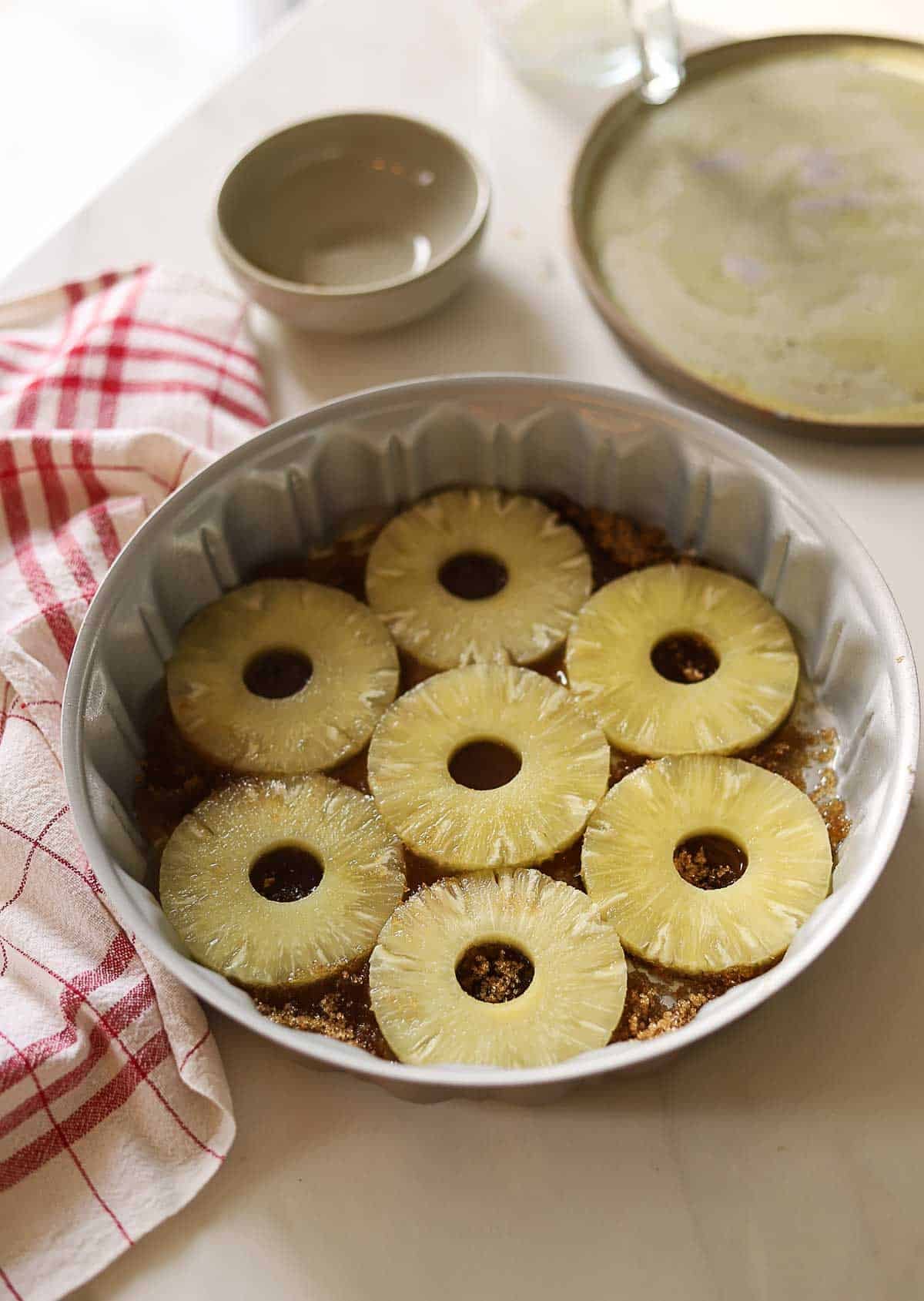 a pineapple upside down cake pan filled with brown sugar and butter and pineapple rings.