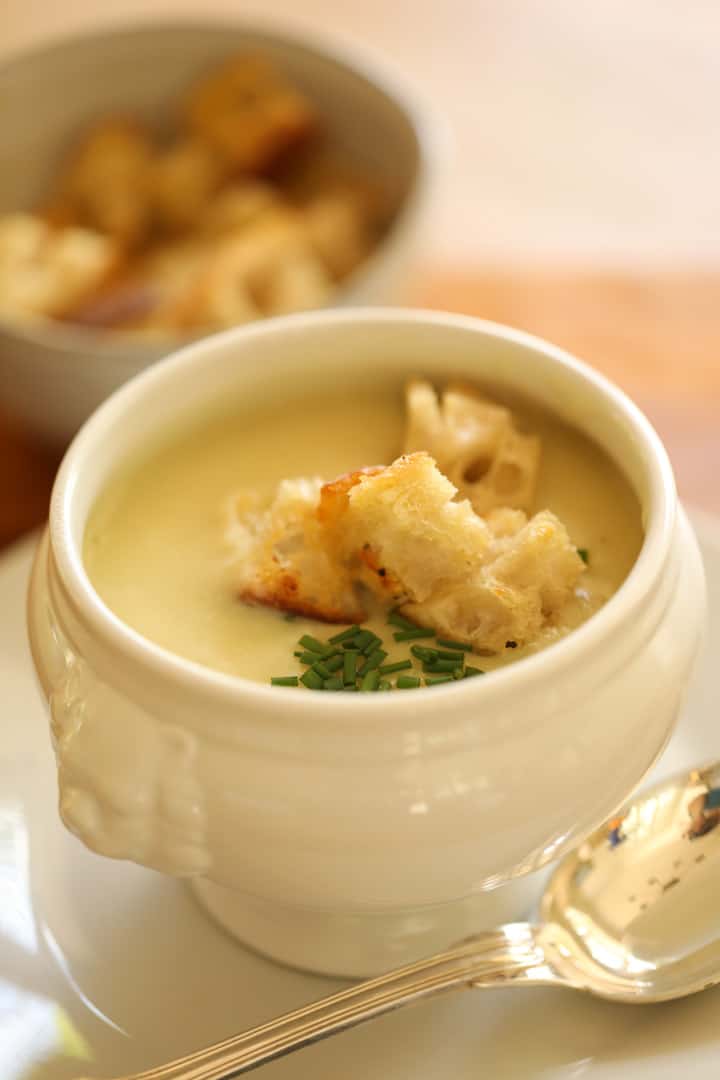 a white soup bowl filled with potato leek soup