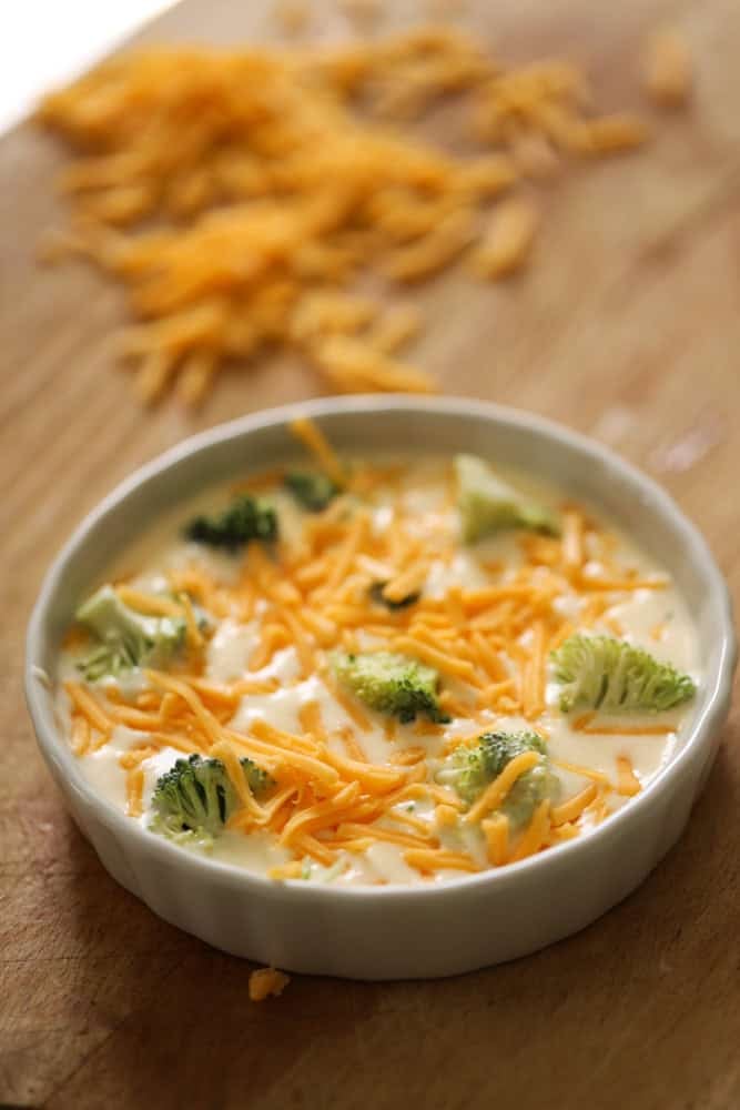 Quiche custard filled in ceramic dish with broccoli and cheddar cheese. 