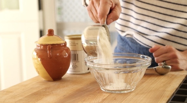 adding flour to a small clear bowl
