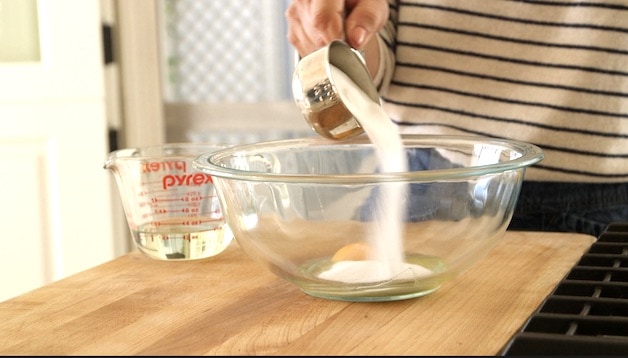 adding sugar to eggs in a large clear bowl