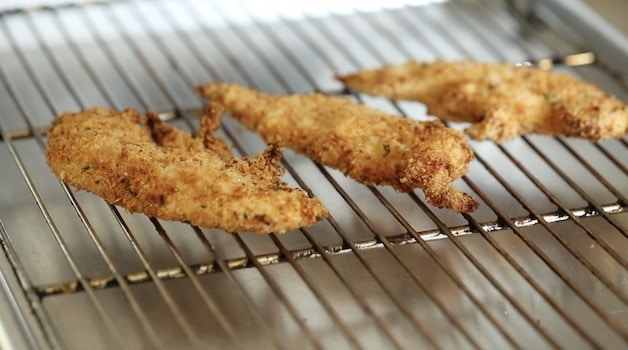 Chicken Tenders fried resting on a baking sheet with rack