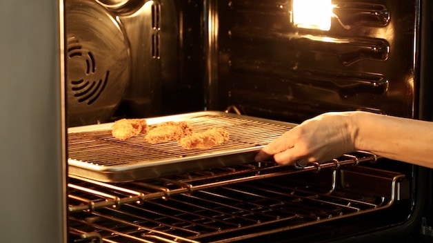 Placing chicken tenders in an oven to keep warm