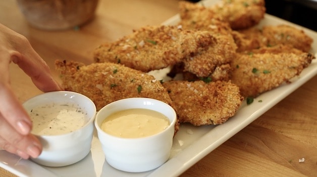 Chicken tenders on a platter with ranch and honey mustard dipping sauces