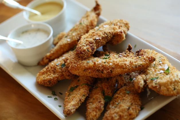 Air Fryer Chicken Tenders on a white platter with dipping sauces