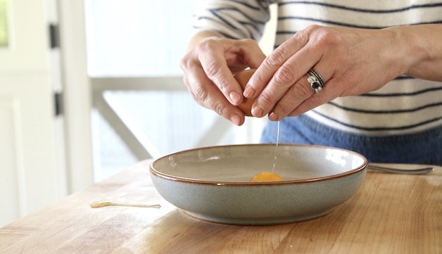 adding eggs to a blue bowl