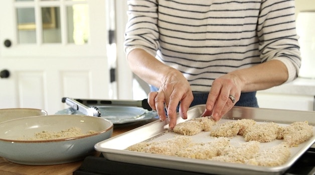 Placing chicken tenders ready to be air fried on a baking sheet