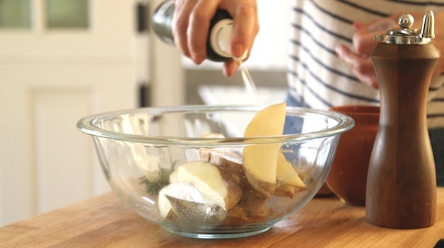 Potato Wedges in bowl being sprayed with oil