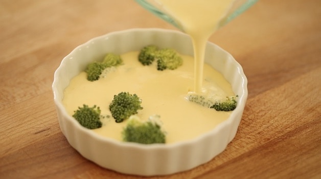 pouring egg custard over broccoli florets