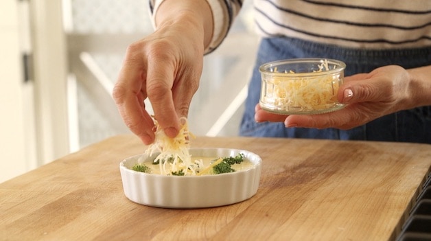 adding shredded cheese to quiche