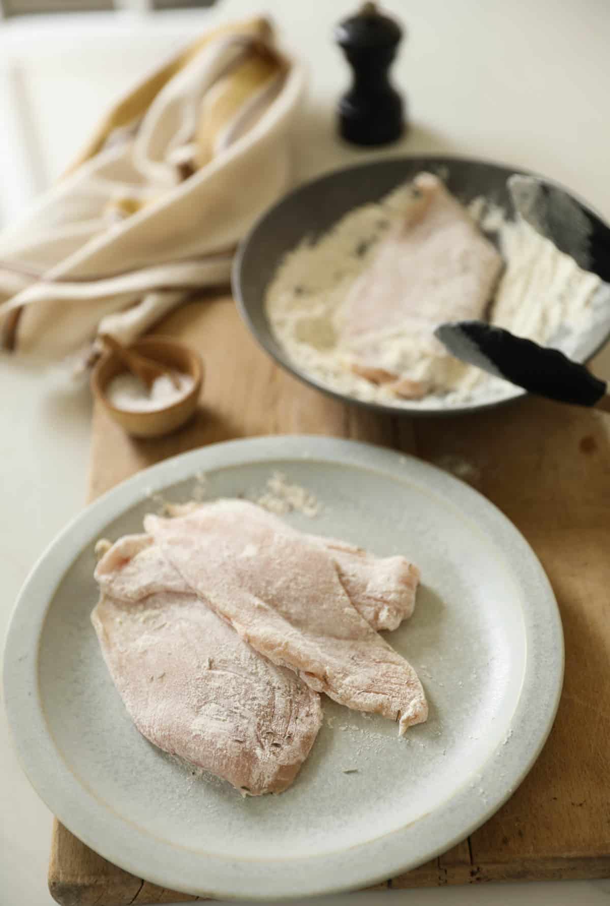 chicken cutlets being dredged in flour and seasonings.