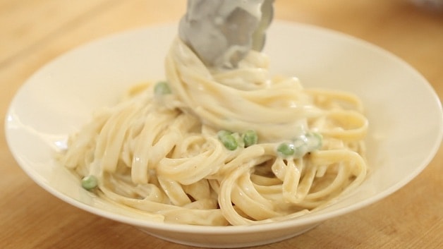 twisting fettuccine with tongs in a bowl