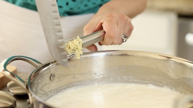 adding garlic to cream in a skillet
