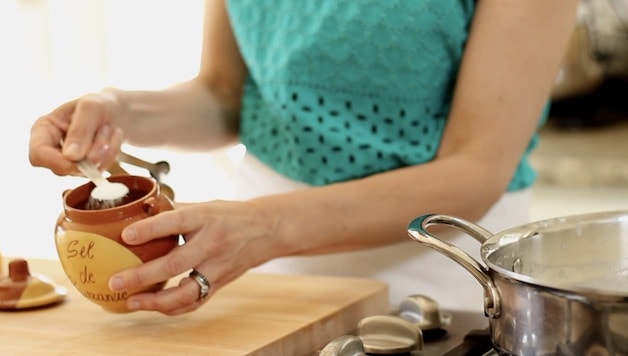 Ading salt from a salt pot to a skillet