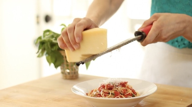 Adding pamesean to pasta with tomato sauce