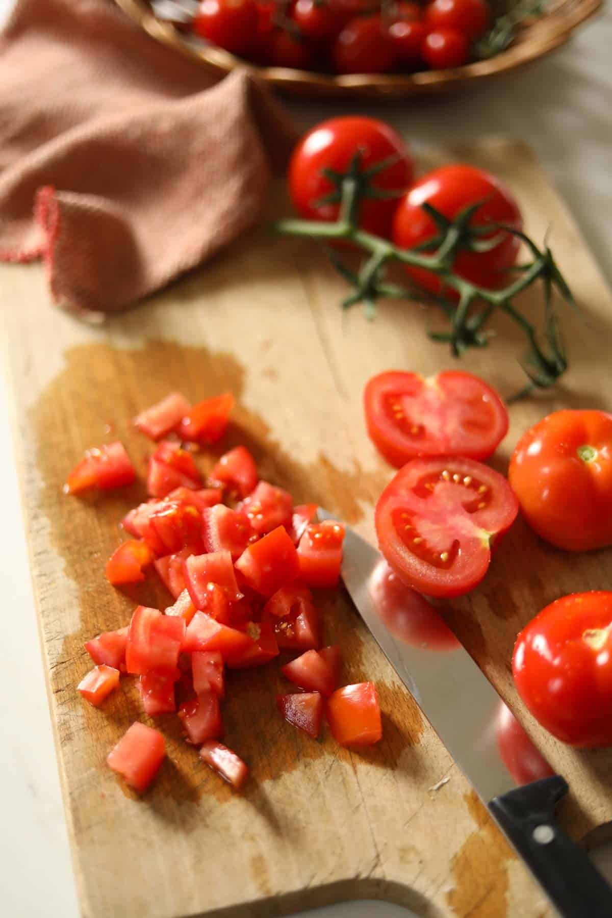 tomatoes diced on a cutting board with a knife.