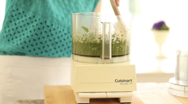 Scraping down pesto with a spatula in a food processor