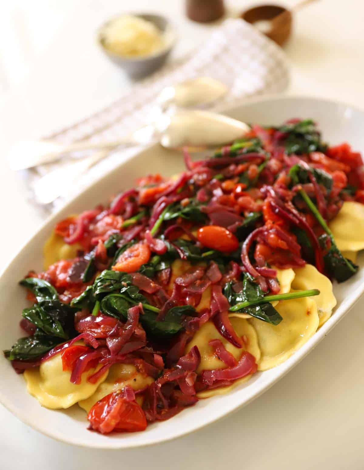 A platter of ravioli topped with healthy sautéed veggies.
