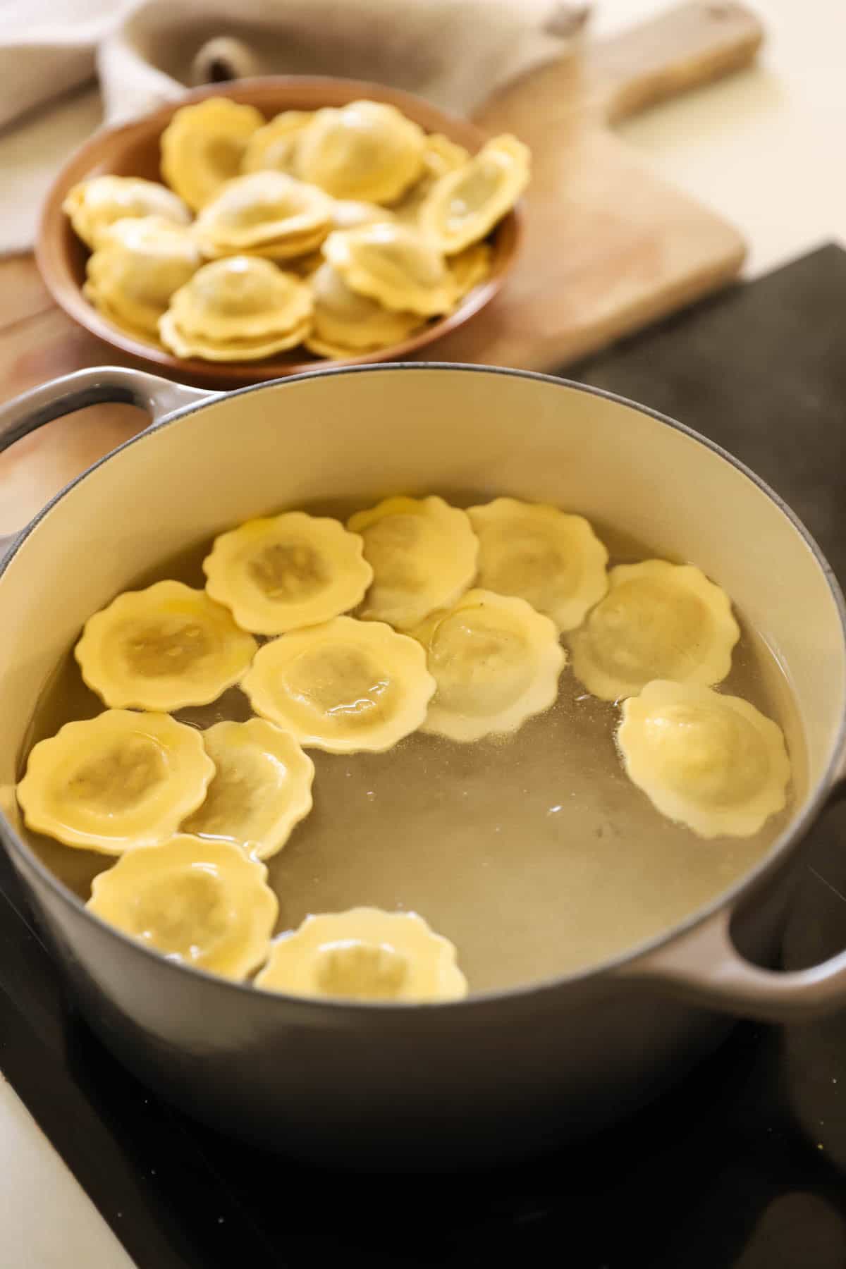 Spinach ravioli cooking in a large pot of boiling water.