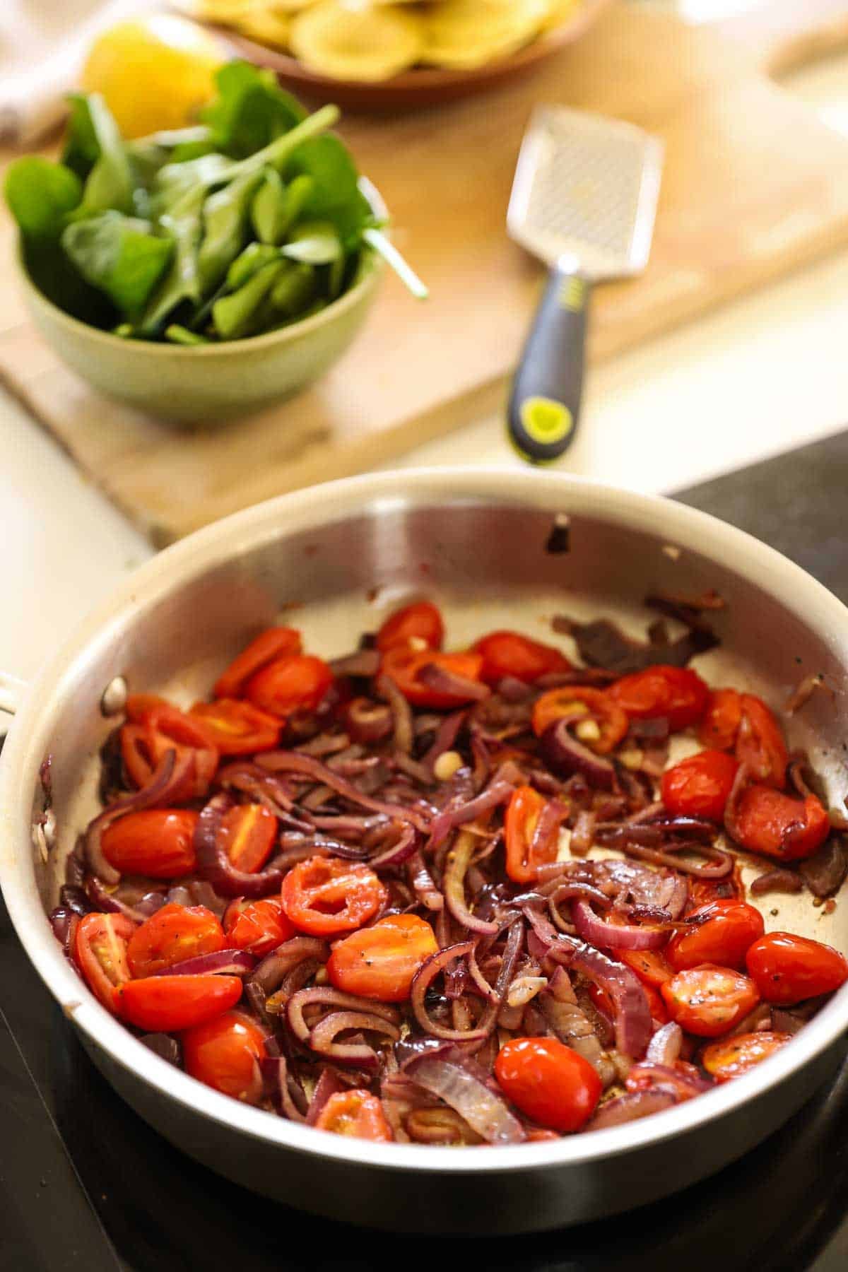 caramelized red onions and cooked cherry tomatoes in a skillet.