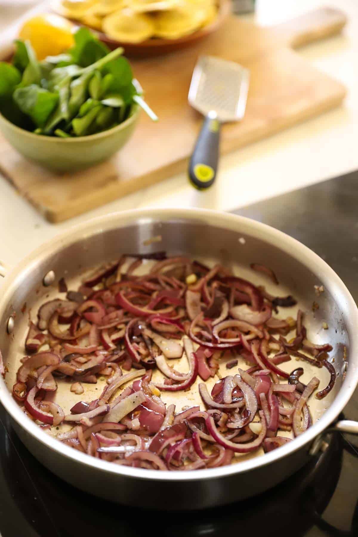 Onions Caramelizing in a stainless steel skillet.