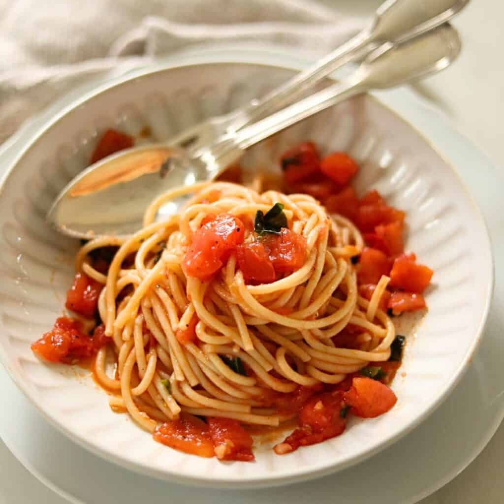 A bowl of spaghetti with fresh tomato sauce and basil