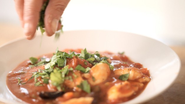 adding parsley to the top of a chicken stew