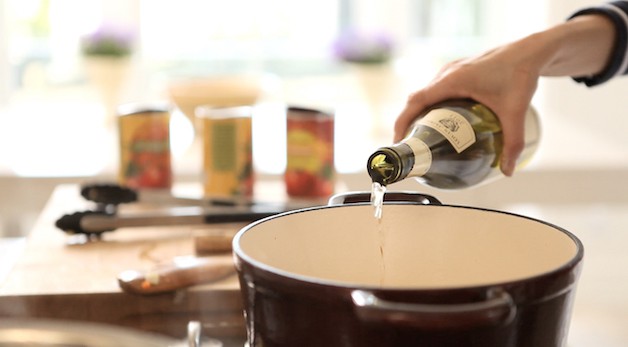 adding white wine to a stew pot