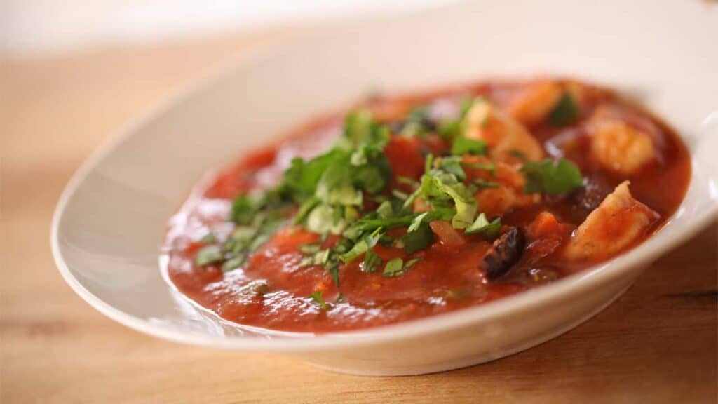 A close up of a bowl of food on a plate, with Chicken and Stew