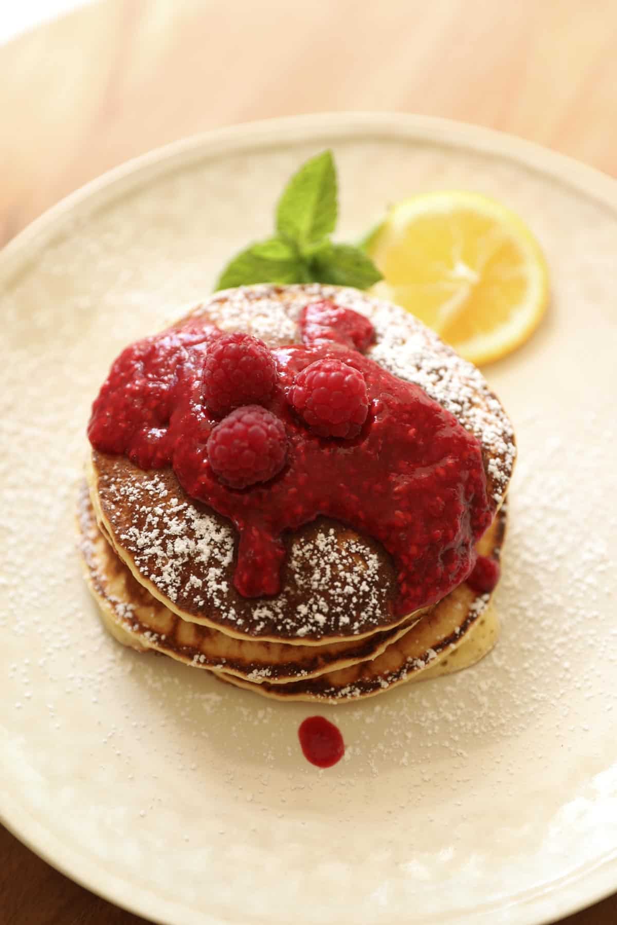 A stack of pancakes topped with pureed raspberry sauce