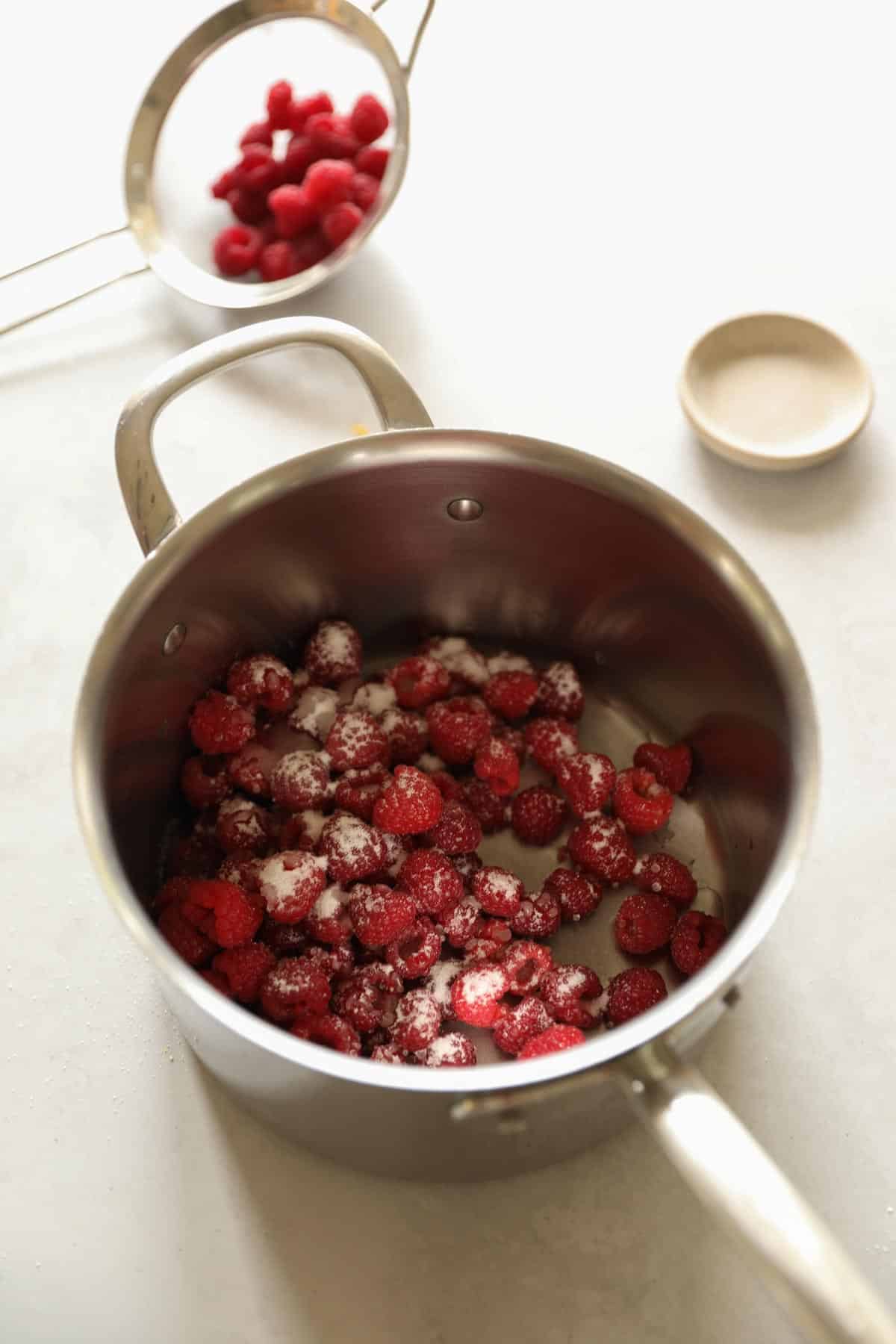 A pot with fresh raspberries, sugar and water