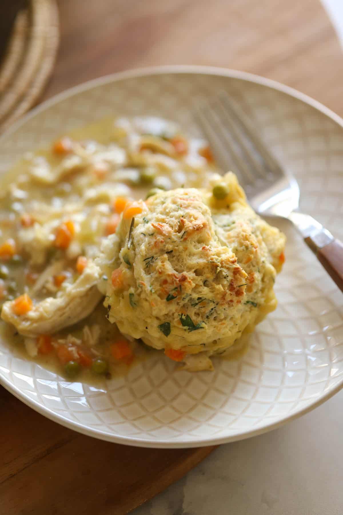 a plate with chicken and biscuits with a fork