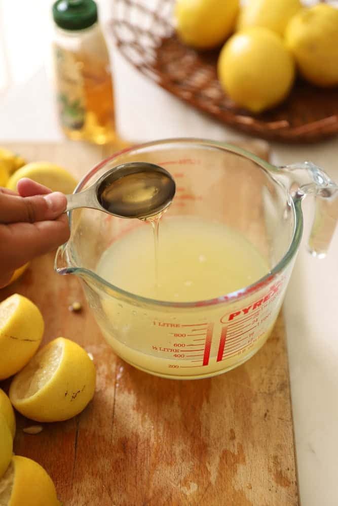 adding a tablespoon of Agave syrup to a pyrex pitcher filled with lemon juice.