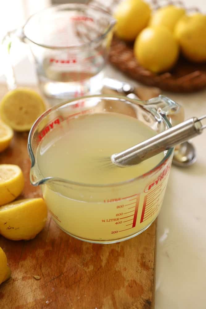 water added to a Pyrex pitcher to create lemonade.