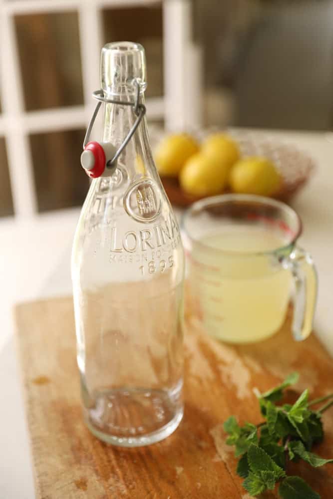 an empty French Lemonade bottle on a cutting board, with lemonade in the background.