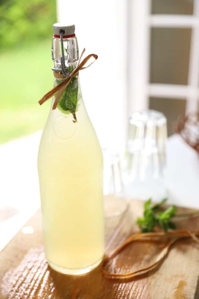 A bottle filled with lemonade and topped off with fresh mint leaves.