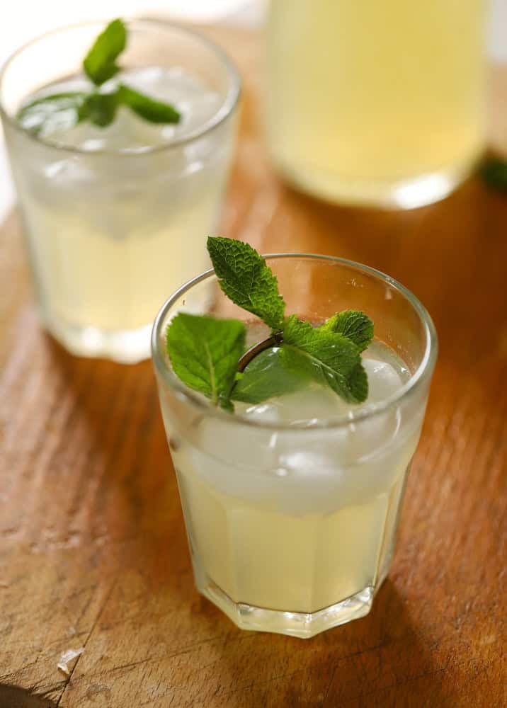 Two glasses of lemonade garnished with ice and fresh mint.