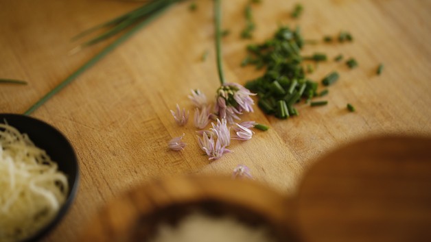 Minced chives and purple chive blossoms on a plate