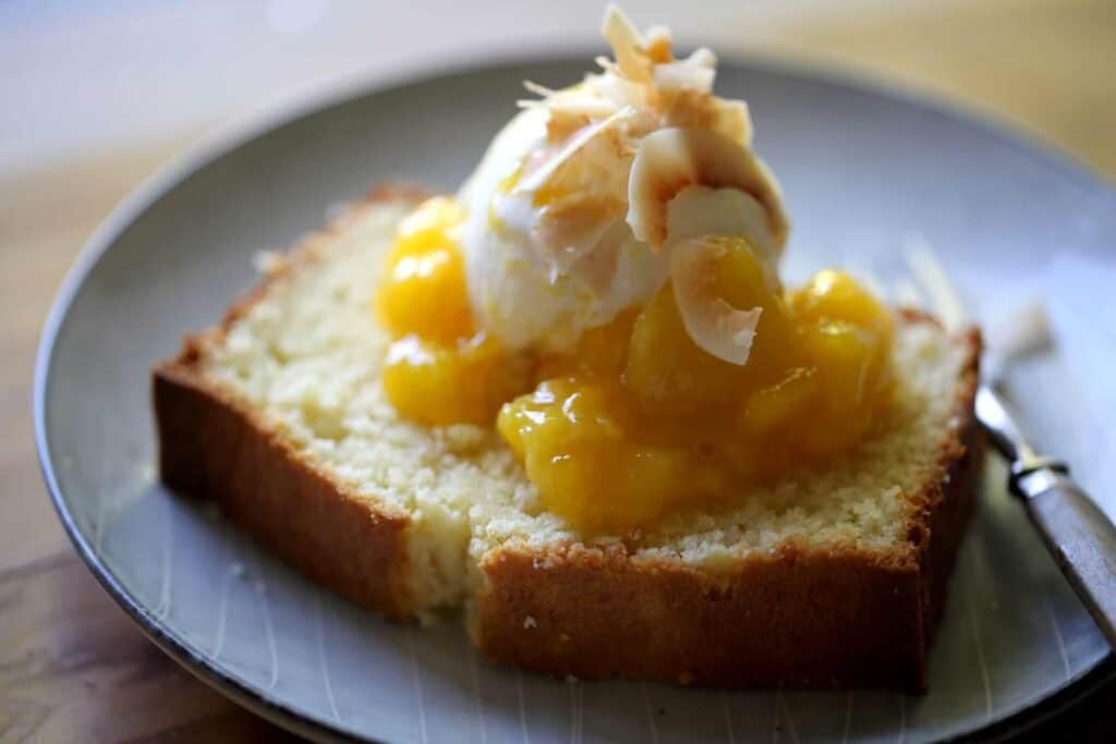 Vanilla Ice Cream and Mango Sauce with Coconut Flakes on top of a slice of coconut pound cake