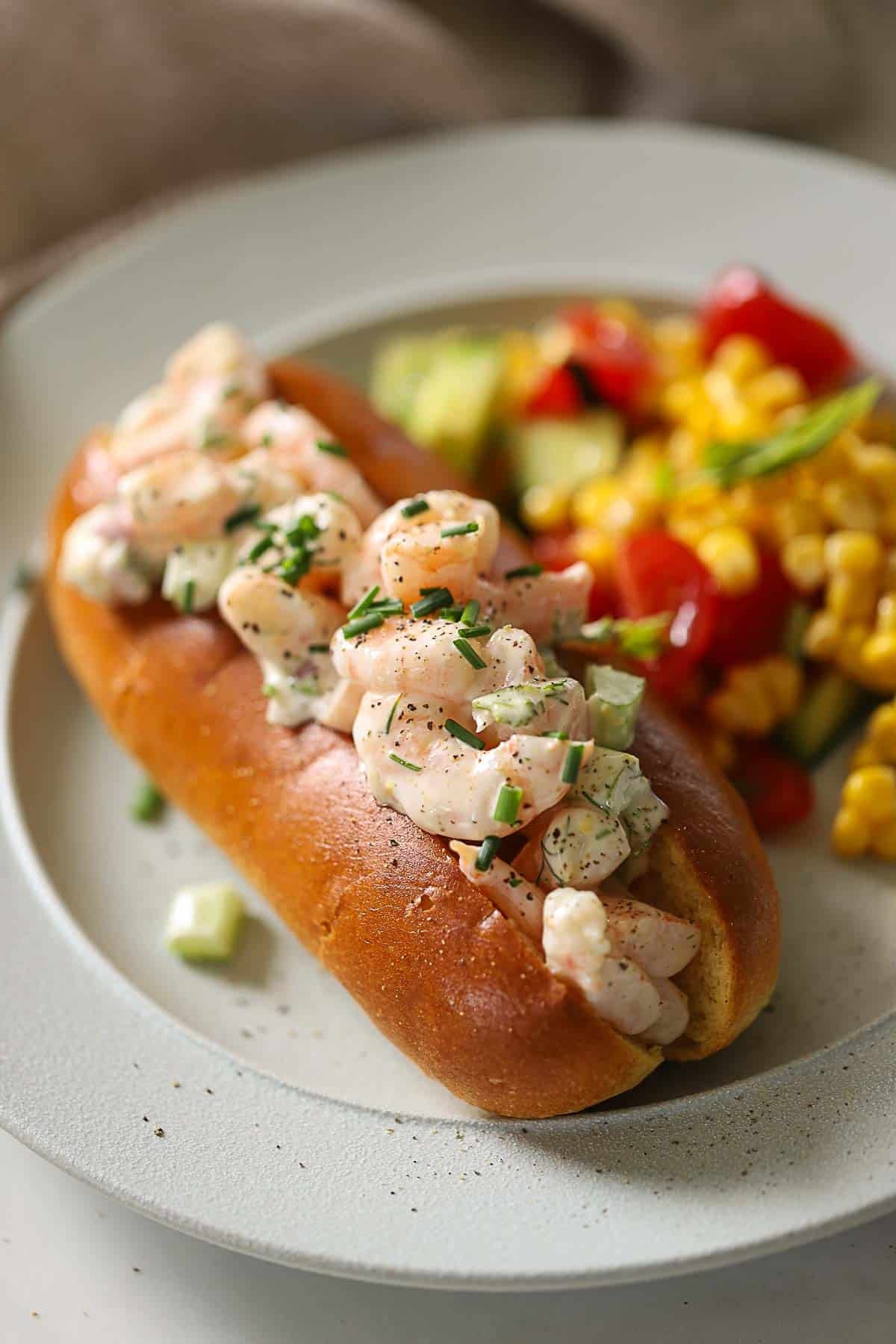 a side angle of a shrimp roll showing shrimp loaded into a split top bun.