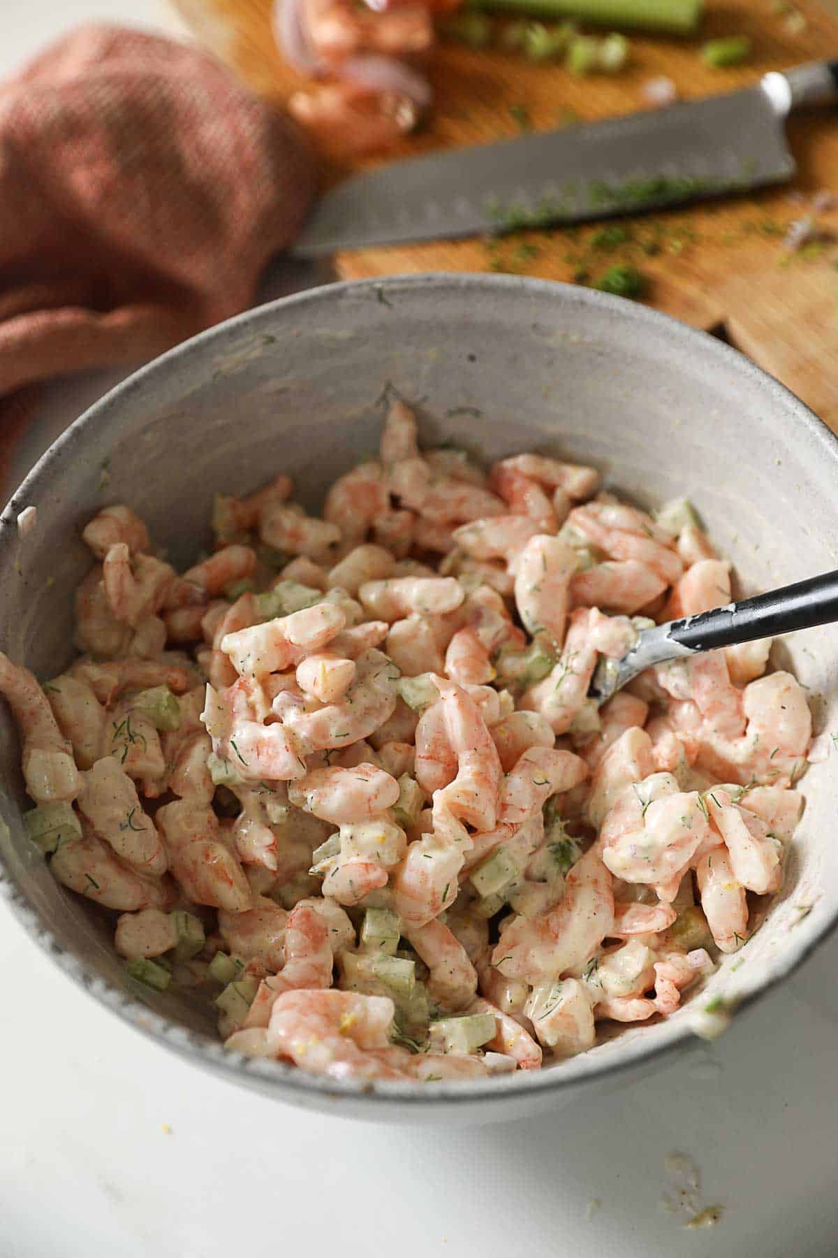 a bowl of shrimp salad tossed in mayonaise.