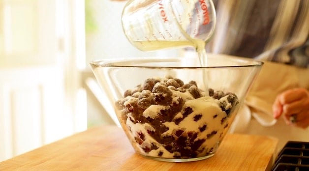 adding water to a blackberry mixture in a clear bowl