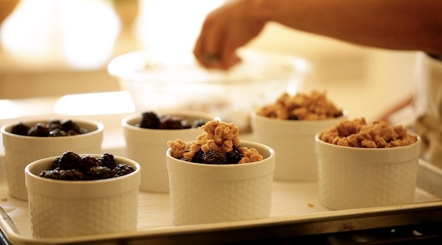 adding crumble to ramekins filled with blackberries